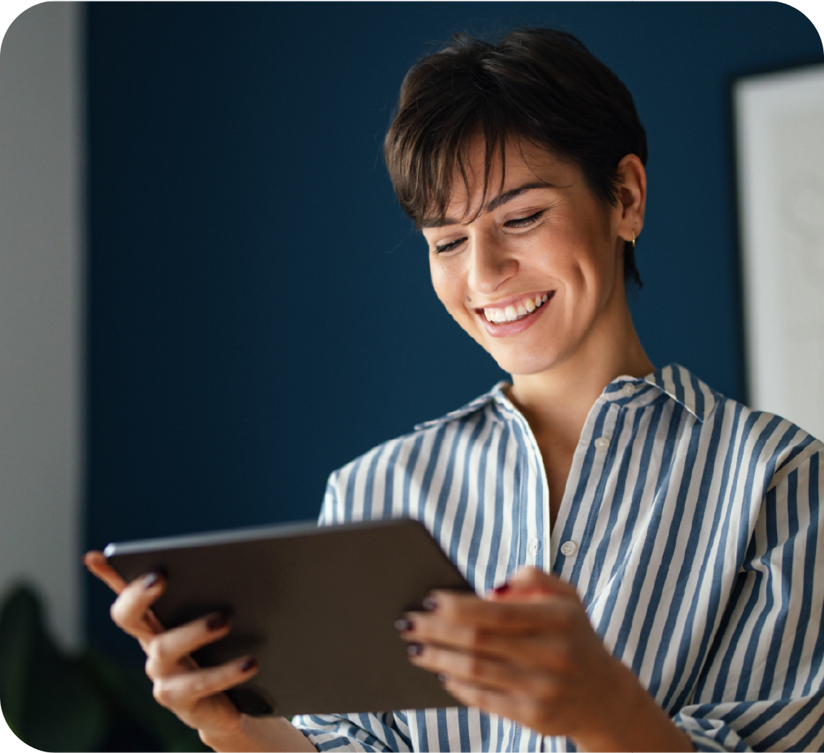 A woman smiling while looking at tablet screen
